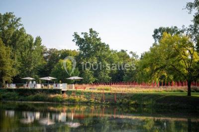 Table de réception élégamment dressée avec nappes blanches, verres, couverts, fleurs et bouteilles disposés harmonieusement.