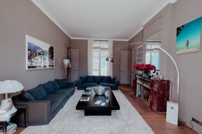 Bouteilles de vin rouge sur une table dressée avec des verres, des fleurs et une personne ajustant un couvert.