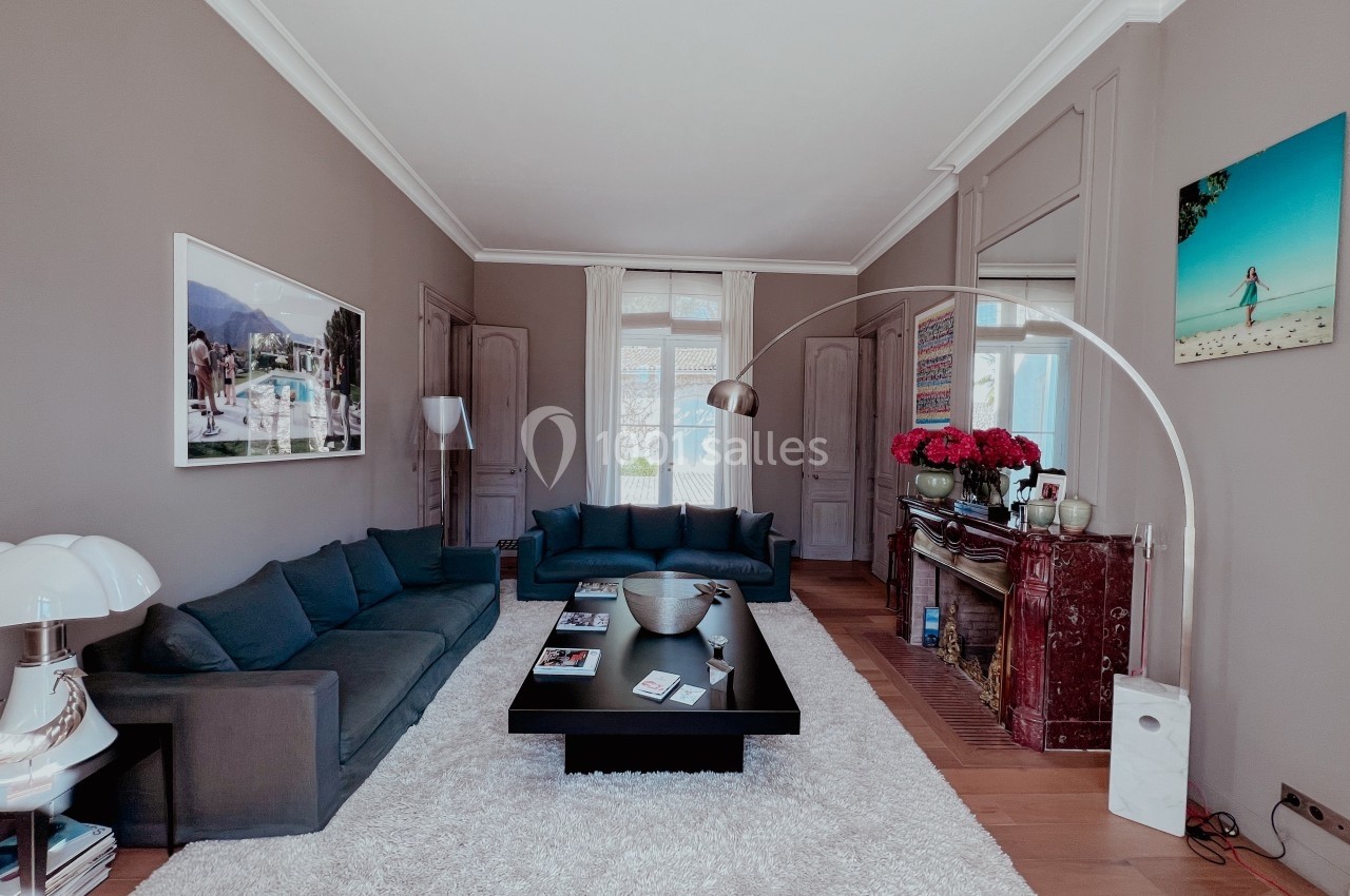 Salon élégant avec canapé gris, table basse noire, cheminée en marbre rouge, et décoration soignée dans un intérieur…