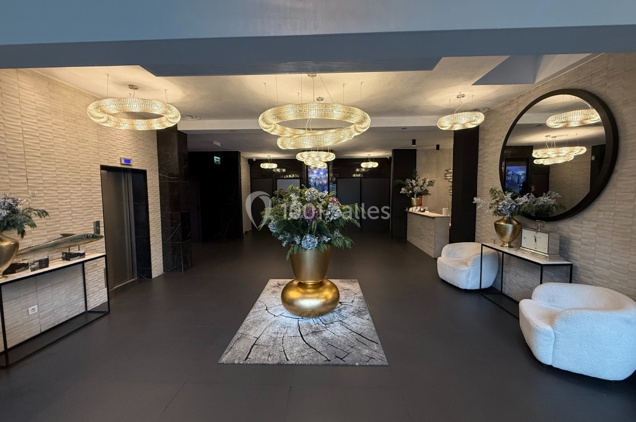 Accueil Square Hall d'entrée élégant avec un grand vase doré central, des lustres modernes et des fauteuils blancs.