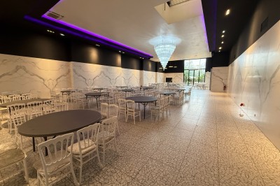 Miniature Salle villa Salle de conférence moderne avec des rangées de chaises noires, sol en marbre et toit vitré laissant entrer la lumière…