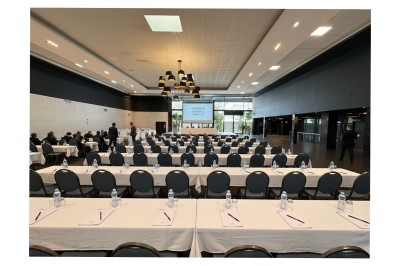 Miniature vote assemblée générale Salle de conférence moderne avec des rangées de chaises noires, sol en marbre et toit vitré laissant entrer la lumière…