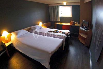 Salon moderne avec canapé, fauteuils en rotin, table basse en verre, décoration minimaliste et murs neutres.