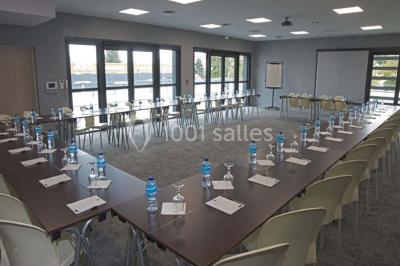 Salon moderne avec canapé, fauteuils en rotin, table basse en verre, décoration minimaliste et murs neutres.