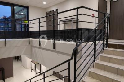 Salon moderne avec canapé, fauteuils en rotin, table basse en verre, décoration minimaliste et murs neutres.