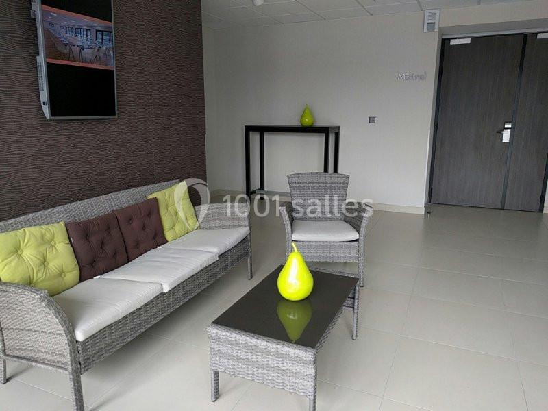 Salon moderne avec canapé, fauteuils en rotin, table basse en verre, décoration minimaliste et murs neutres.