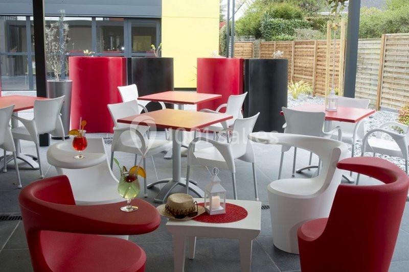 Terrasse moderne avec tables rouges et blanches, chaises assorties et boissons colorées sur les tables.