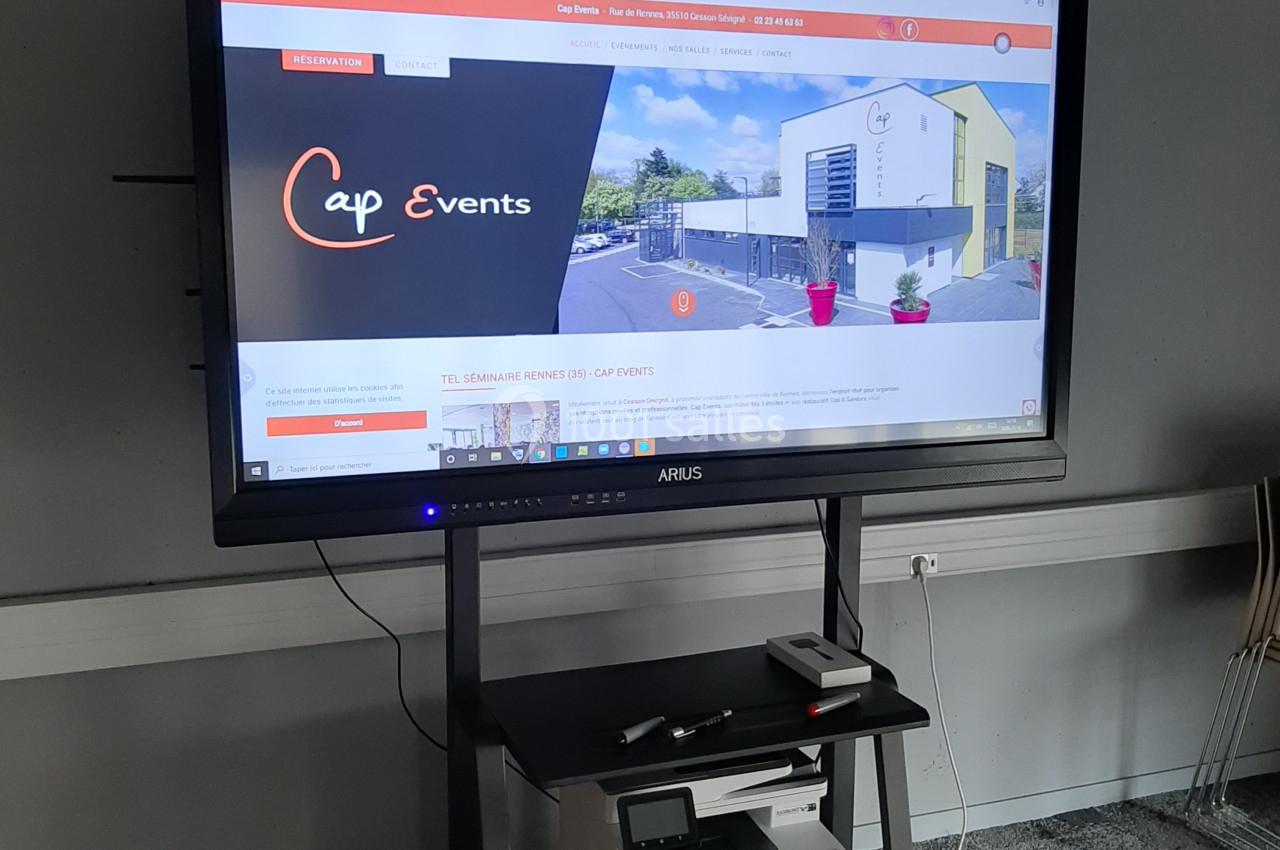 Écran interactif affichant le site web d'une salle événementielle, posé sur un support avec une imprimante en dessous.