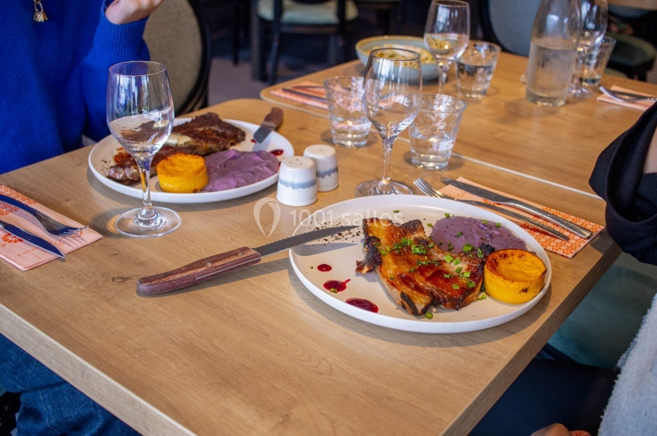 Deux assiettes servies sur une table en bois, contenant des plats garnis de viande, purée violette et accompagnements.