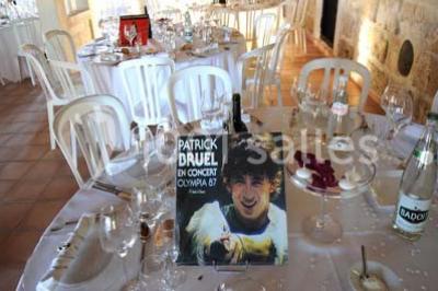 Des musiciens en tenue blanche et rayée jouent des percussions en extérieur, près d'une petite fille.