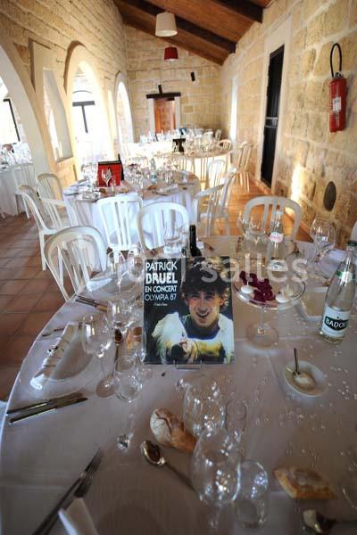 Salle de réception avec tables dressées, décor rustique, et une affiche de concert posée sur une table.