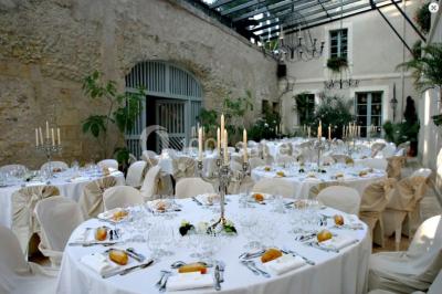 Façade d'un bâtiment ancien en pierre avec une piscine et un jardin arboré sous un ciel bleu.
