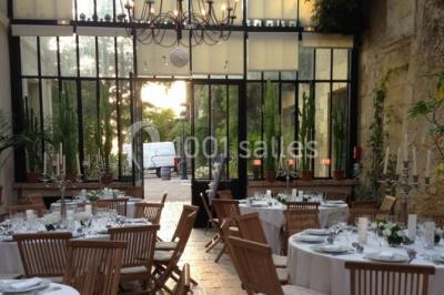 Façade d'un bâtiment ancien en pierre avec une piscine et un jardin arboré sous un ciel bleu.