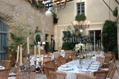 Façade d'un bâtiment ancien en pierre avec une piscine et un jardin arboré sous un ciel bleu.