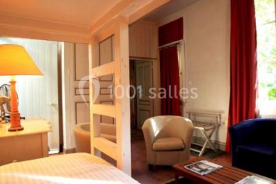 Façade d'un bâtiment ancien en pierre avec une piscine et un jardin arboré sous un ciel bleu.