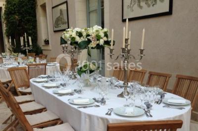 Façade d'un bâtiment ancien en pierre avec une piscine et un jardin arboré sous un ciel bleu.