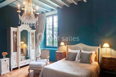 Piscine extérieure avec transats et parasols, entourée de verdure et située près d'une maison en pierre.