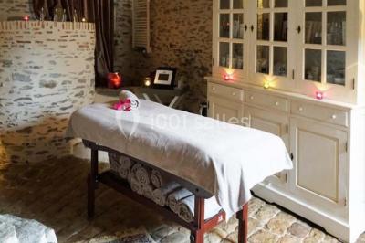 Piscine extérieure avec transats et parasols, entourée de verdure et située près d'une maison en pierre.