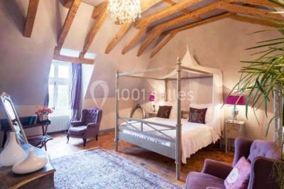 Piscine extérieure avec transats et parasols, entourée de verdure et située près d'une maison en pierre.