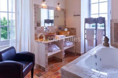 Piscine extérieure avec transats et parasols, entourée de verdure et située près d'une maison en pierre.