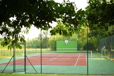 Piscine extérieure avec transats et parasols, entourée de verdure et située près d'une maison en pierre.