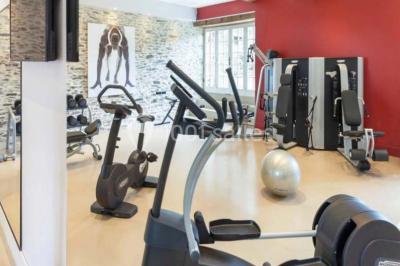 Piscine extérieure avec transats et parasols, entourée de verdure et située près d'une maison en pierre.