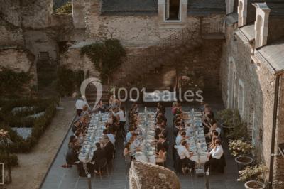 Piscine extérieure avec transats et parasols, entourée de verdure et située près d'une maison en pierre.