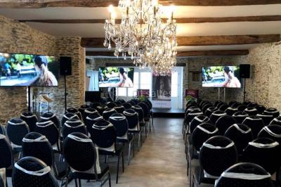 Piscine extérieure avec transats et parasols, entourée de verdure et située près d'une maison en pierre.