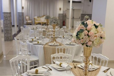 Salle décorée avec un canapé doré, des chaises assorties et une table dressée avec vaisselle élégante et bougies.