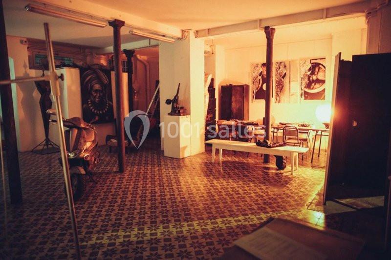 Espace intérieur avec carrelage ancien, mobilier éclectique, éclairage chaleureux et éléments décoratifs artistiques.