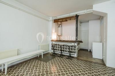 Exposition artistique dans une salle avec des œuvres colorées accrochées aux murs et des photos disposées sur une table.