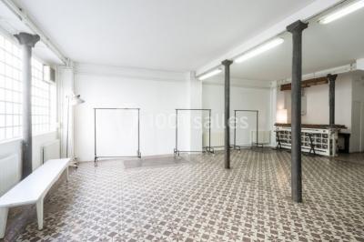 Exposition artistique dans une salle avec des œuvres colorées accrochées aux murs et des photos disposées sur une table.