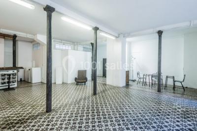 Exposition artistique dans une salle avec des œuvres colorées accrochées aux murs et des photos disposées sur une table.