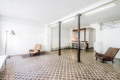 Exposition artistique dans une salle avec des œuvres colorées accrochées aux murs et des photos disposées sur une table.