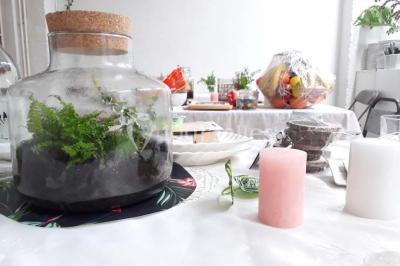 Exposition artistique dans une salle avec des œuvres colorées accrochées aux murs et des photos disposées sur une table.