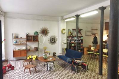 Exposition artistique dans une salle avec des œuvres colorées accrochées aux murs et des photos disposées sur une table.