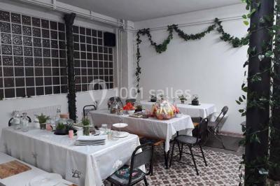 Exposition artistique dans une salle avec des œuvres colorées accrochées aux murs et des photos disposées sur une table.