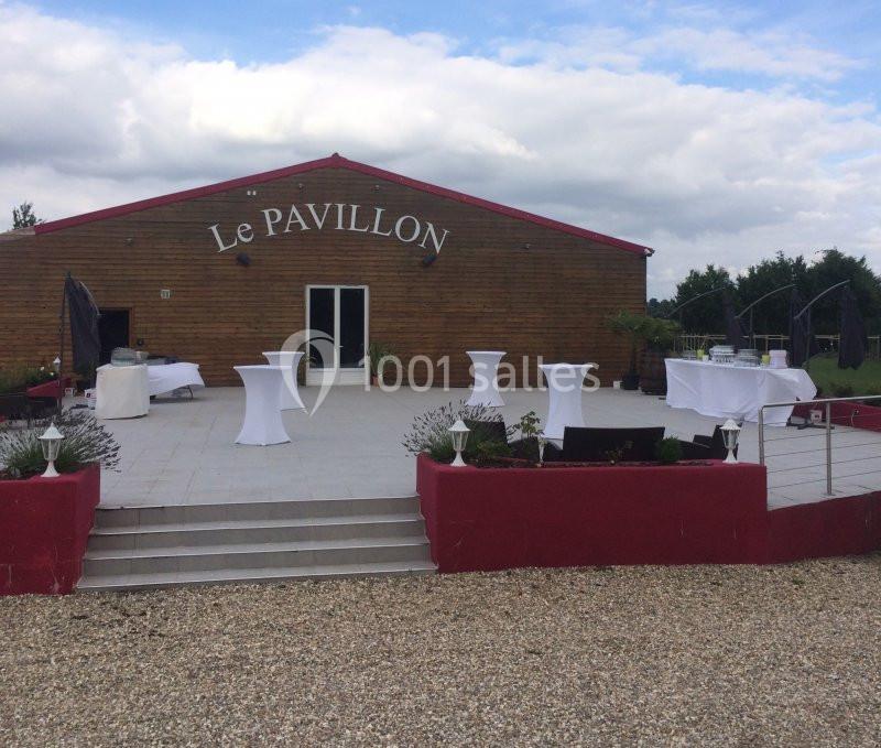Salle de réception avec terrasse aménagée, tables hautes blanches et décorations extérieures simples.
