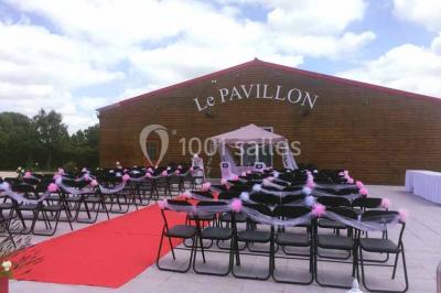 Parking extérieur rempli de voitures, avec un homme debout près d'une Audi noire sous un ciel dégagé.