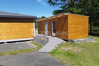 Maisons en rangée avec façades en bois, entourées d'arbres et d'espaces verts, sous un ciel dégagé.