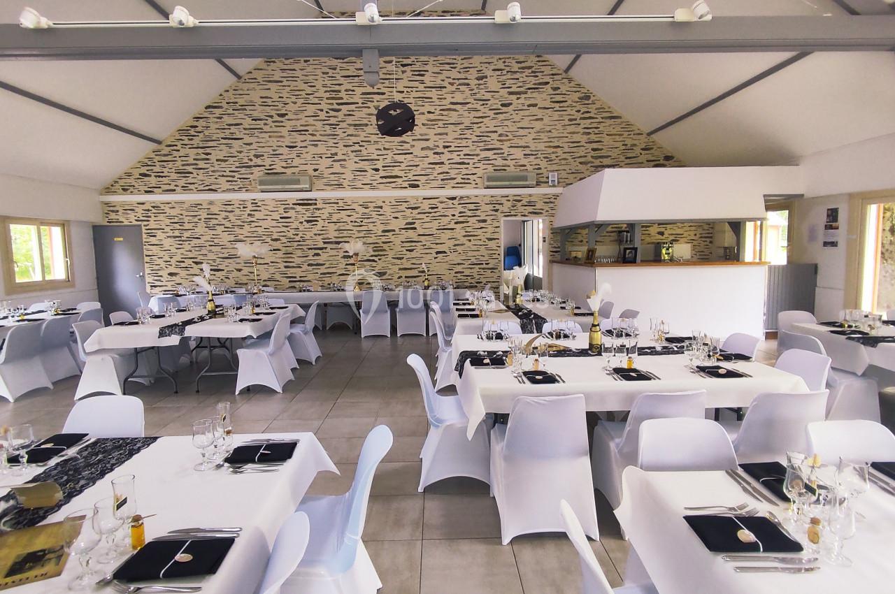 Salle de réception lumineuse avec tables dressées, nappes blanches et décoration élégante.