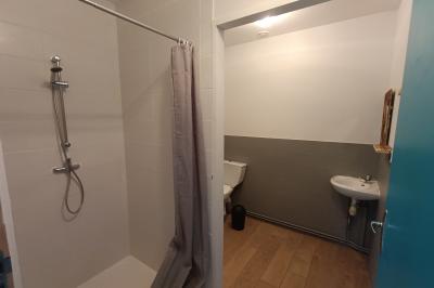 Maisons en rangée avec façades en bois, entourées d'arbres et d'espaces verts, sous un ciel dégagé.