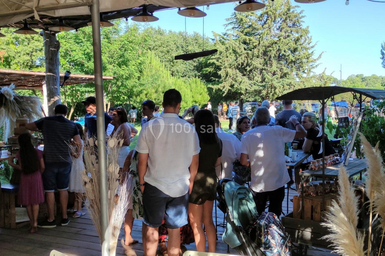 Groupe de personnes rassemblées dans un marché en plein air, entourées de végétation et de stands artisanaux.