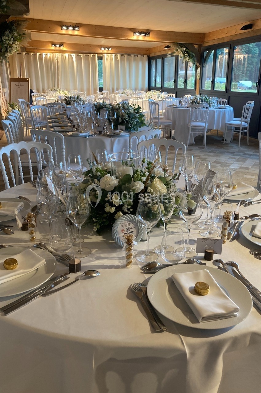 Tables élégamment dressées pour un événement, avec nappes blanches, vaisselle raffinée et centres de table fleuris.