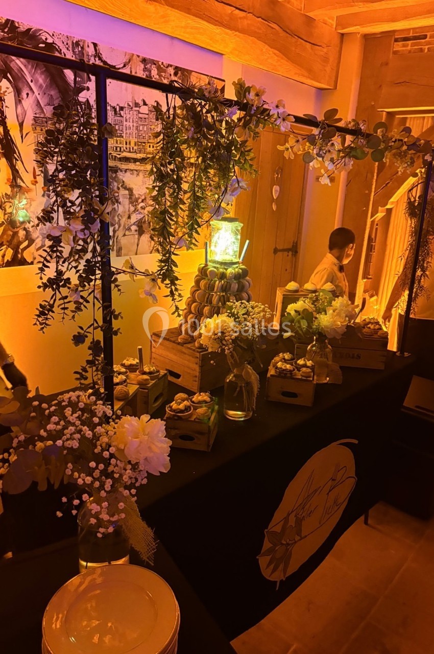 Table décorée avec des fleurs, des plantes suspendues et des desserts, dans une ambiance chaleureuse et tamisée.