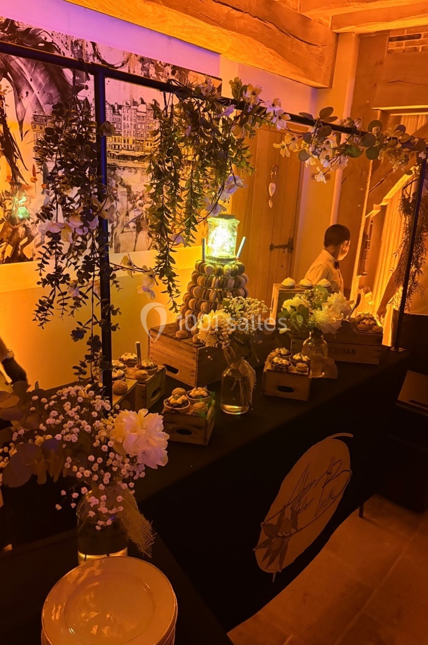 Table décorée avec des fleurs, des plantes suspendues et des desserts, dans une ambiance chaleureuse et éclairage tamisé.