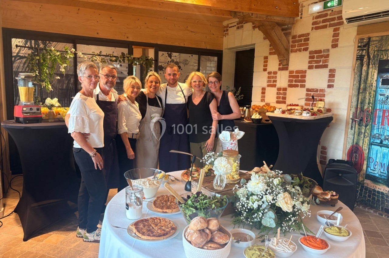 Un groupe de personnes posant devant une table garnie de plats et de décorations dans une salle lumineuse.