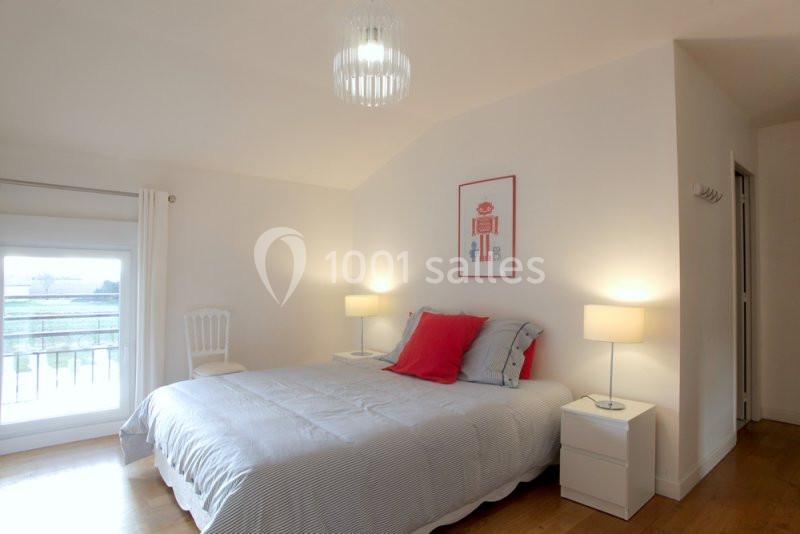 Chambre lumineuse avec un lit double, deux tables de chevet, lampes allumées et une fenêtre donnant sur l'extérieur.