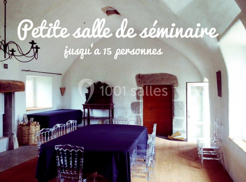 Salle de séminaire lumineuse avec murs blancs, tables noires, chaises transparentes et mobilier ancien en bois.