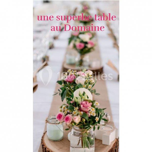 Centre de table avec bouquets de fleurs roses et blanches sur une table décorée pour un événement.